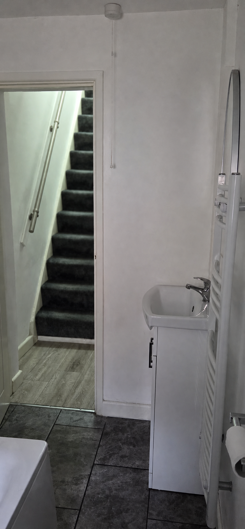 Completed bathroom with staircase visible through the doorway